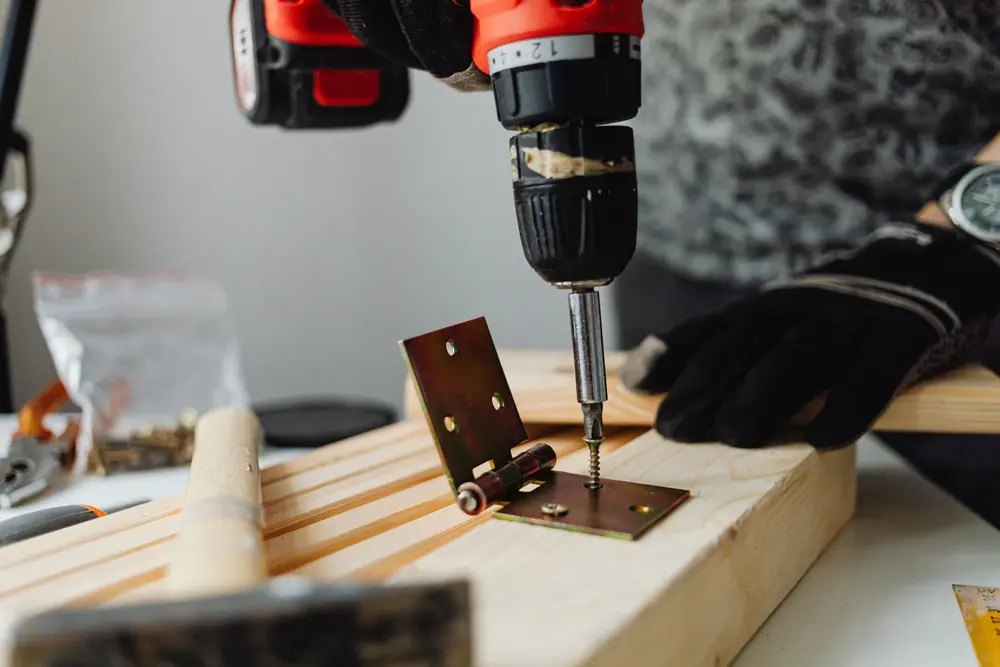 Carpenter drilling hinge screws for door replacement in Nashua, NH